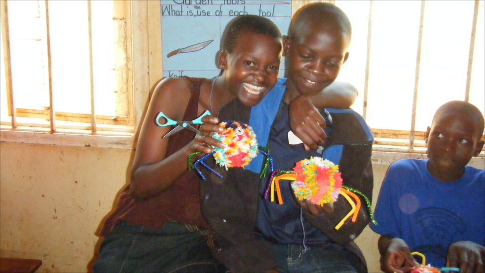 Ugandan children holding some woollen spiders they have made in a craft class