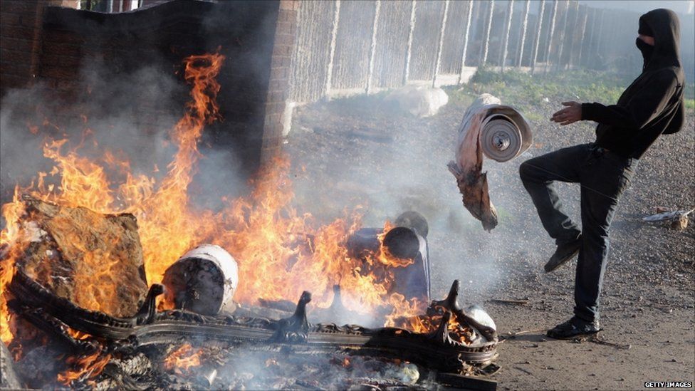 Protesters feed a fire from the remains of a burnt caravan during evictions from Dale Farm travellers camp on 19 October, 2011