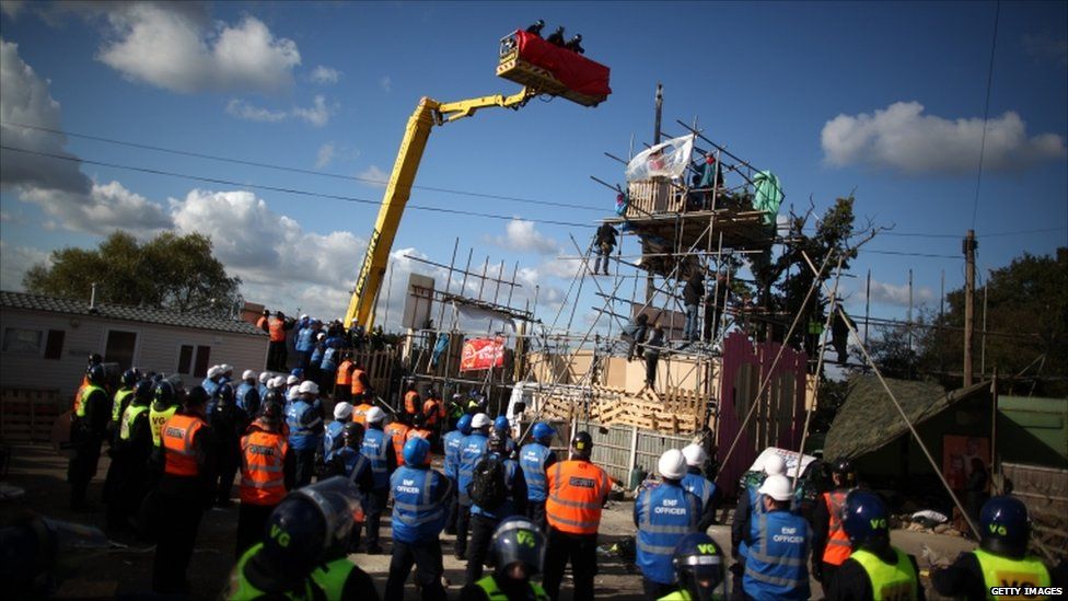 Police rise up in a cherry picker to talk to protestors stood on a scaffold platform during evictions from Dale Farm travellers camp on 19 October, 2011