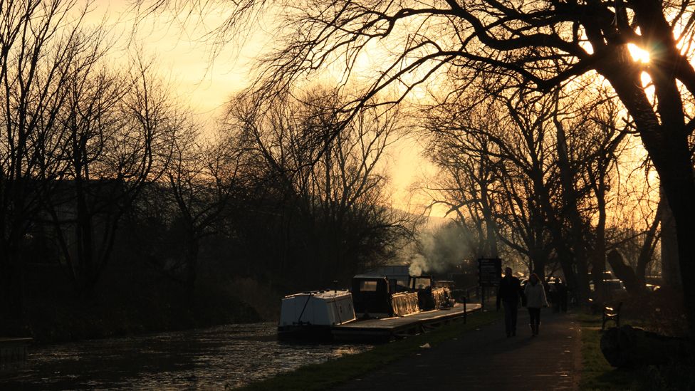 People walking by a barge on a canal