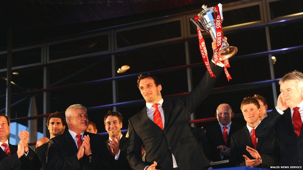 Wales coach Warren Gatland looks on as captain Sam Warburton lifts the Six Nations trophy