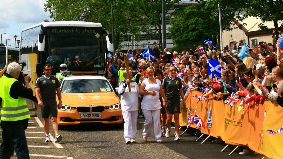 Crowds watch the Olympic torch as it passes