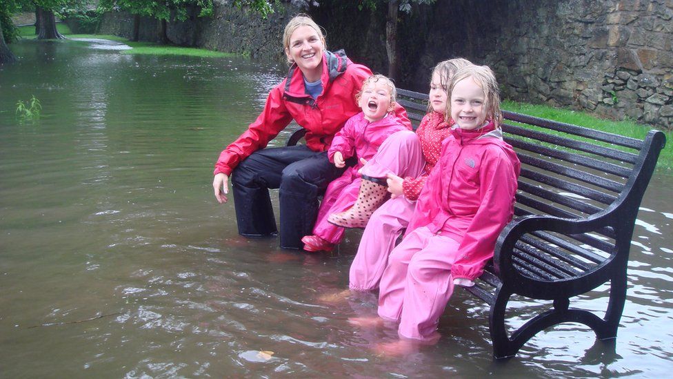 Isla, Maisie and Isobel and mum Jo sitting on a park bench