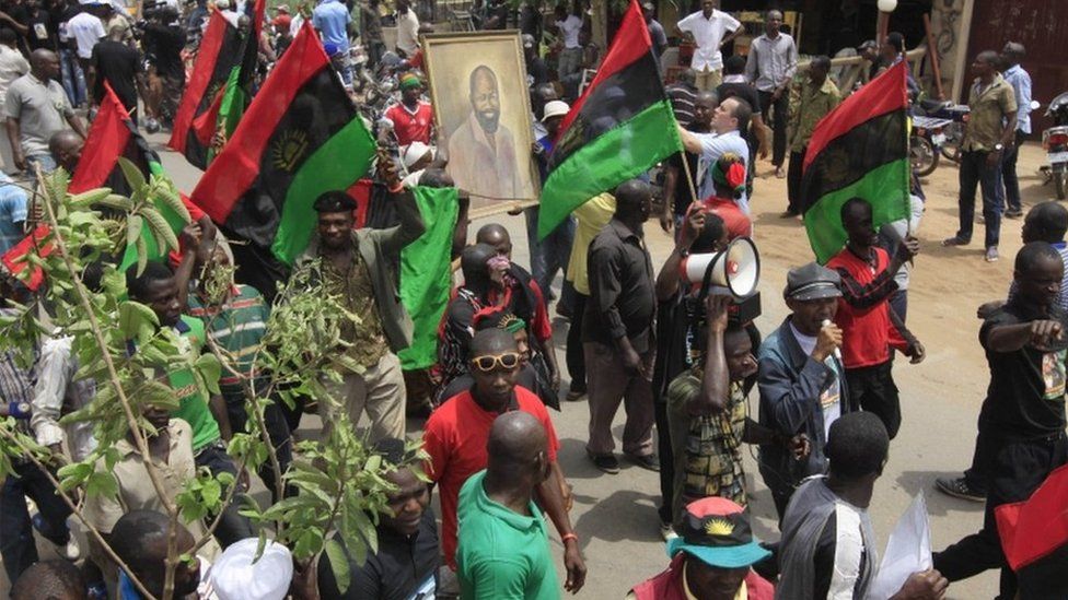 people holding a portrait of Col Ojukwu and waving Biafran flags