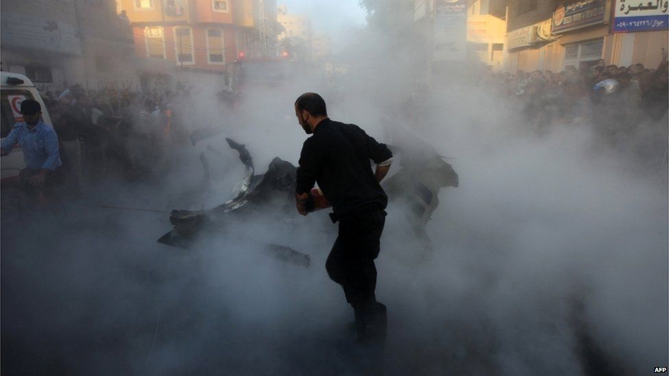 Palestinian firefighters extinguish the blaze on the burning wreckage.