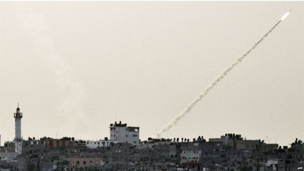 A missile and its vapour trail streak across the sky above Gaza City