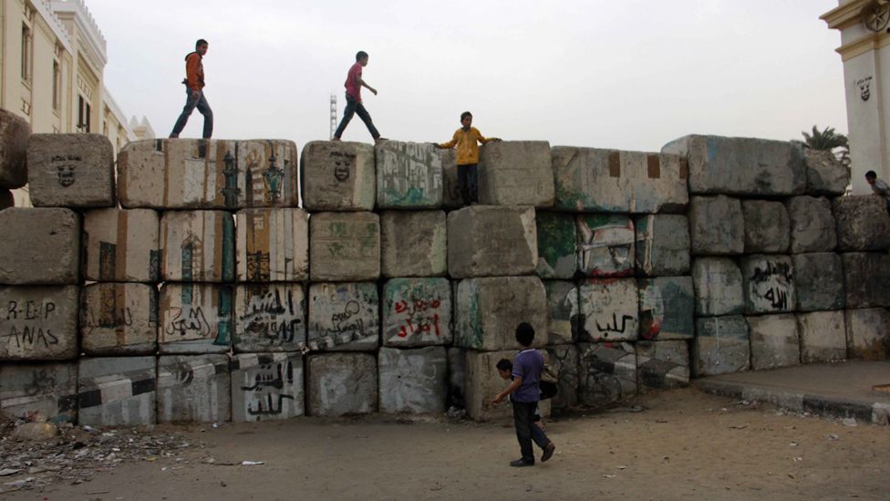 Young men and children climb on the wall that blocks Qasr al-Aini street from the Cabinet building