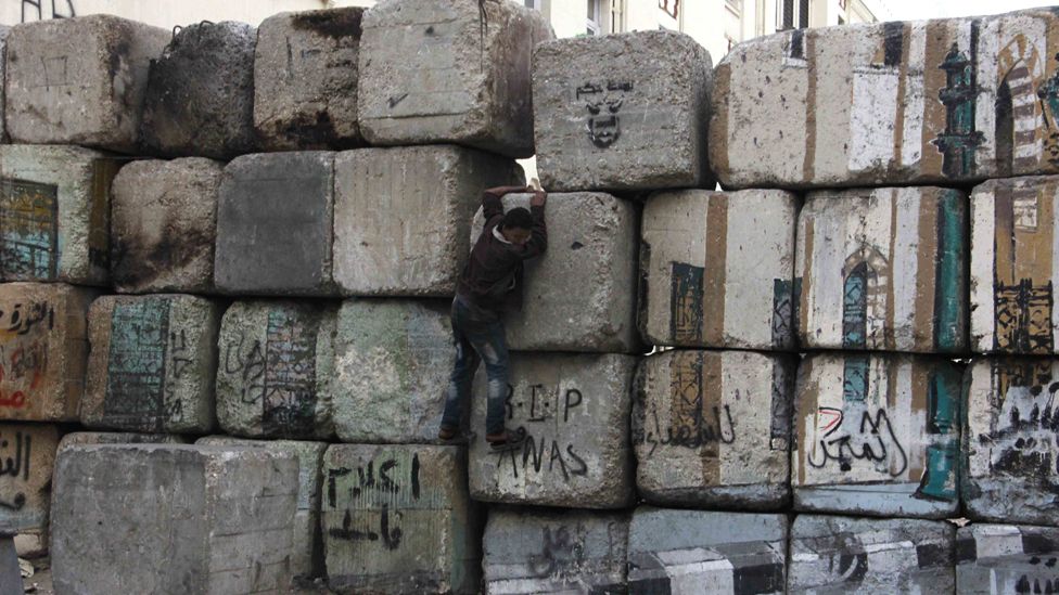 A young man climbs on the wall that blocks Qasr al-Aini street from the Cabinet building, Cairo.
