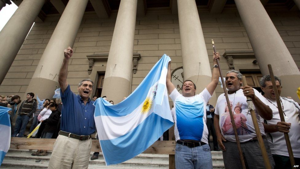 Faithful hold up an Argentine flag and sing outside the Metropolitan Cathedral in Buenos Aires, Argentina