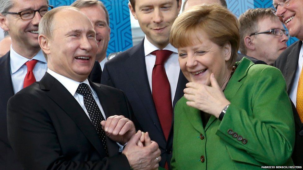 Russian President Vladimir Putin holds the hand of German Chancellor Angela Merkel as they visit the Russian booth during a tour through the Hanover Messe on the first day of the industrial trade fair