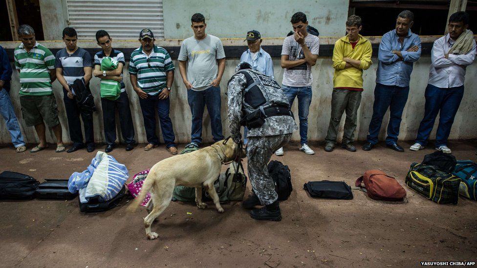 A Brazilian national force agent and his sniffer dog inspect bags