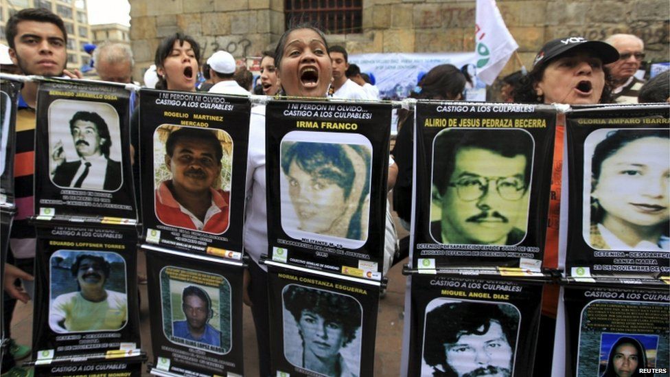 Protesters hold up banners with the pictures of victims and the slogan "I neither forgive nor forget, punish the guilty!"