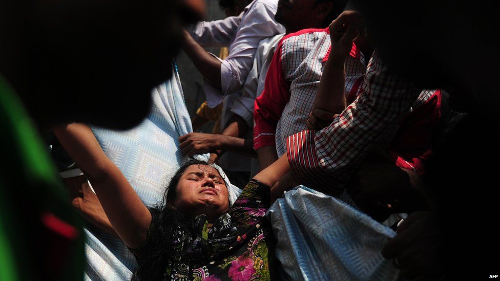 Bangladeshi garment workers assist an injured a survivor after an eight-storey building collapsed in Savar, on the outskirts of Dhaka, on April 24, 2013.