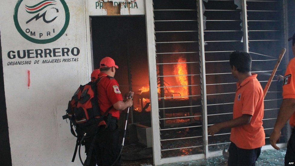 Firefighters try to extinguish a fire at the PRI party offices in Chilpancingo