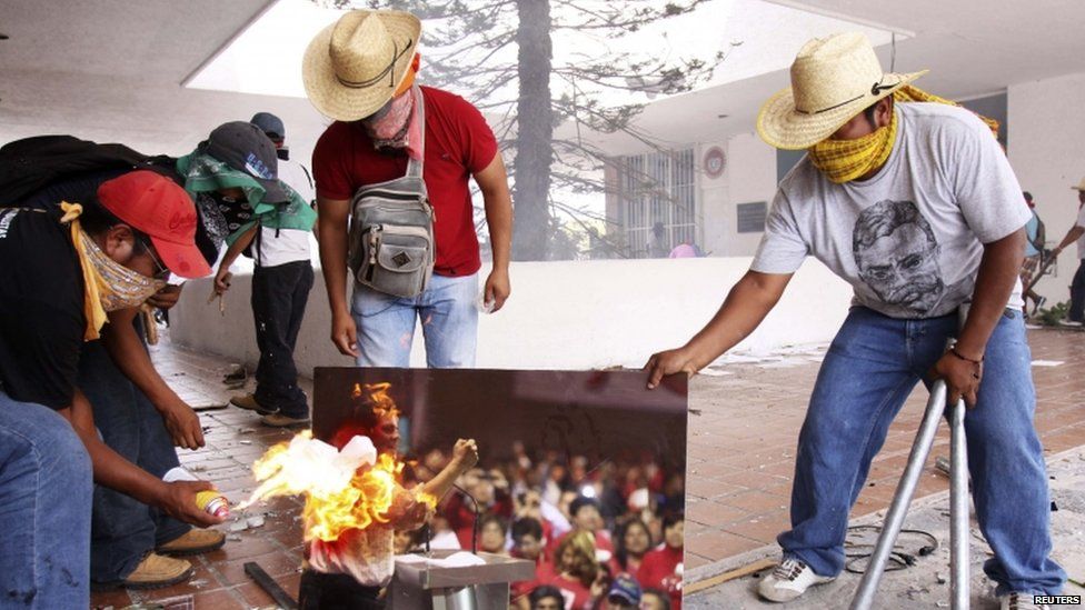 Protesters burn a picture of Mexican President Enrique Pena Nieto