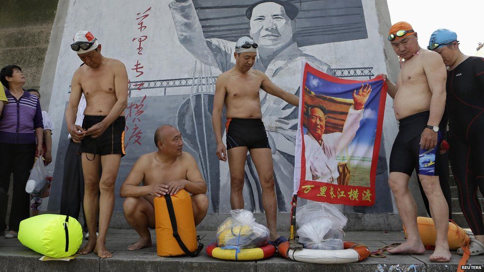 Swimmers hold a flag with an image of the late Chinese leader Mao Zedong, before they set off swimming in the Yangtze to mark International Labour Day in Wuhan, Hubei province, May 1, 2013.