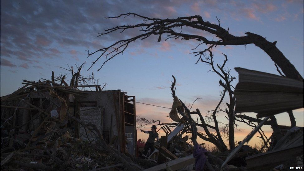 A woman searches for possessions at sunset after the suburb of Moore, Oklahoma was left devastated by a tornado, 21 May 2013
