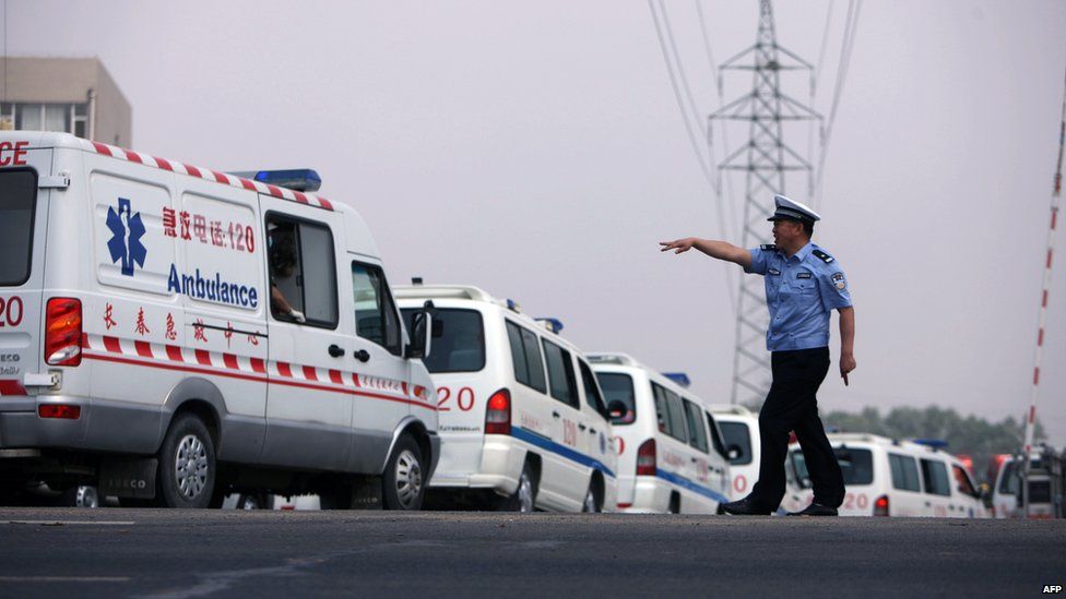 A police officer directs an ambulance outside Baoyuan poultry plant at Dehui, in north-east China's Jilin province, following a factory fire, 3 June 2013