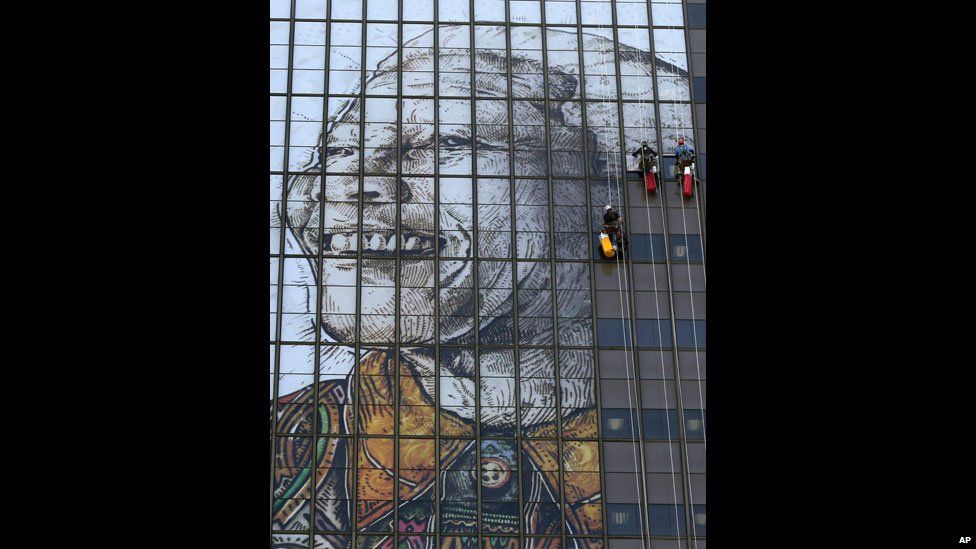 Workers put up a portrait of Nelson Mandela on the windows of a building in Cape Town, South Africa - Thursday 13 June 2013