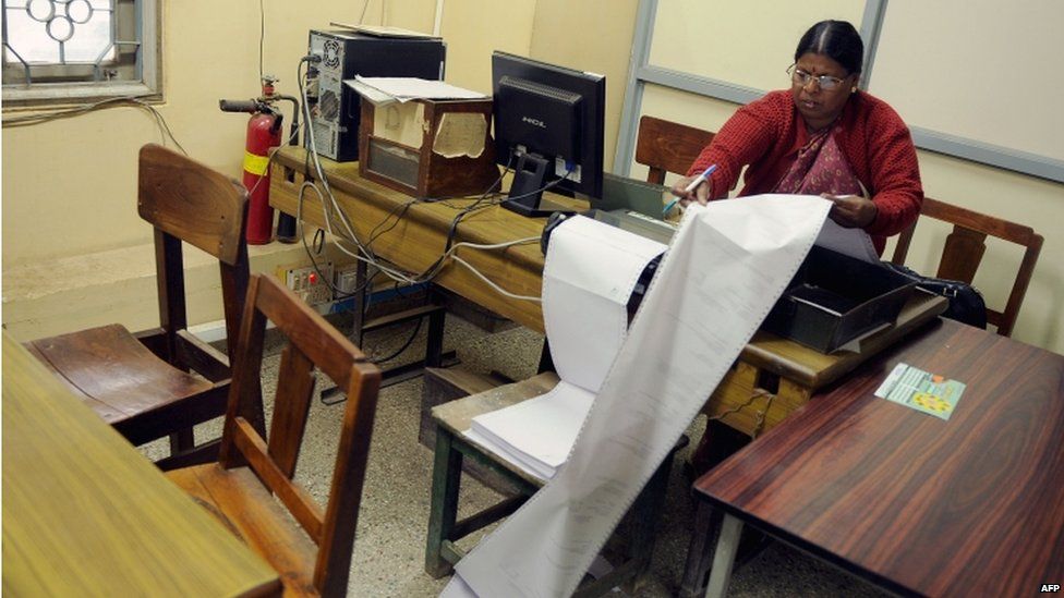 An employee sorts incoming telegrams printed on a continuous sheet of paper at a telecommunications office in Bangalore on June 13, 2013