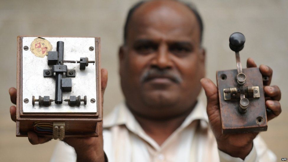 An employee displays an antique telegraph transmitter key (R), which the operator uses to send messages using Morse code, and a telegraph receiver (L) at a telecommunications office in Bangalore on June 13, 2013