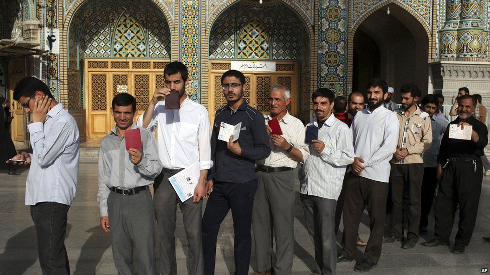Iranian men display identification cards as they line up to vote in Qom. 14 June 2013.