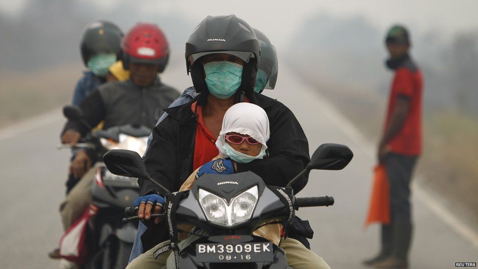 People wear surgical masks as they ride motorcycles in Dumai, Indonesia's Riau province, June 22