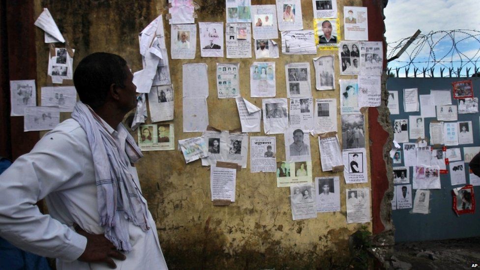 A man looks at a wall which is covered with special announcements and pictures of missing people near the airport gate in Jollygrant, Uttarakhand