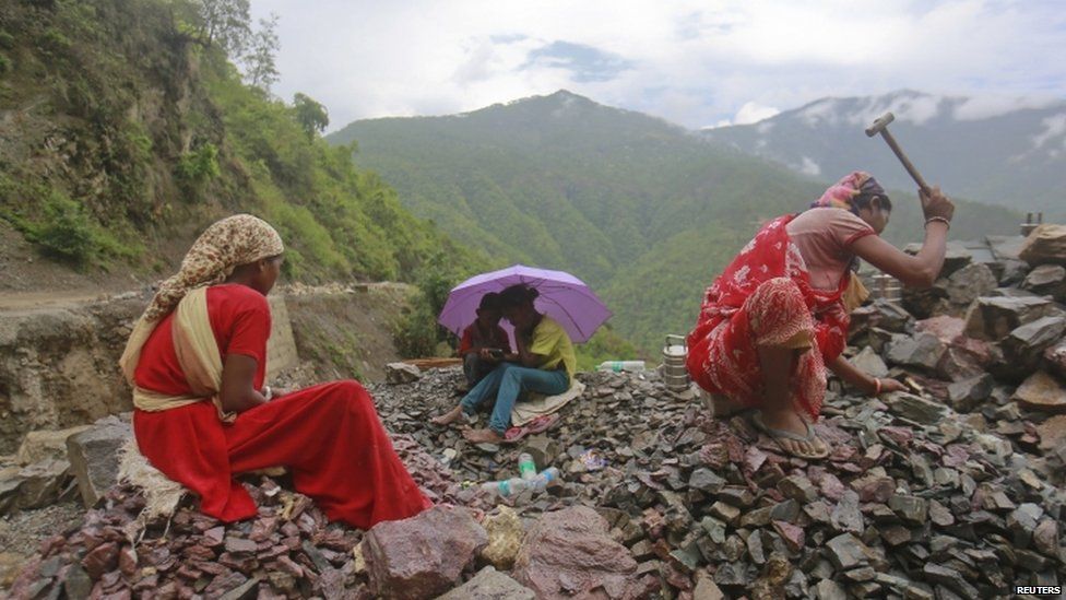 Workers repair a road damaged by a landslide in Uttarakhand