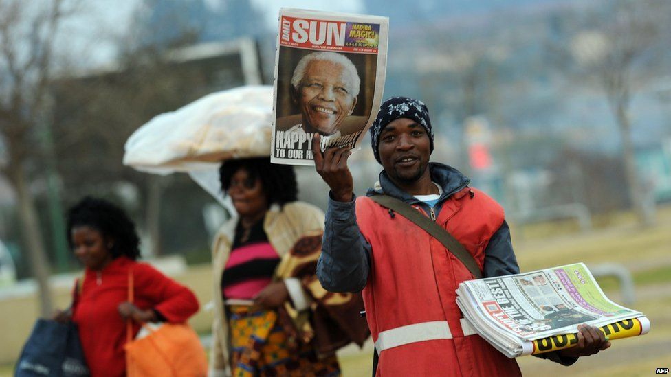 Newspaper vendor holds up paper with Mandela's picture on the front, Soweto (18 July)