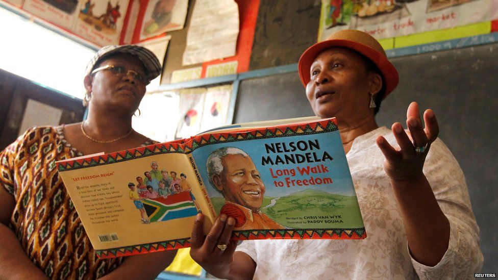 Two women read from a children's version of Nelson Mandela's autobiography to a school class in Nairobi (18 July)