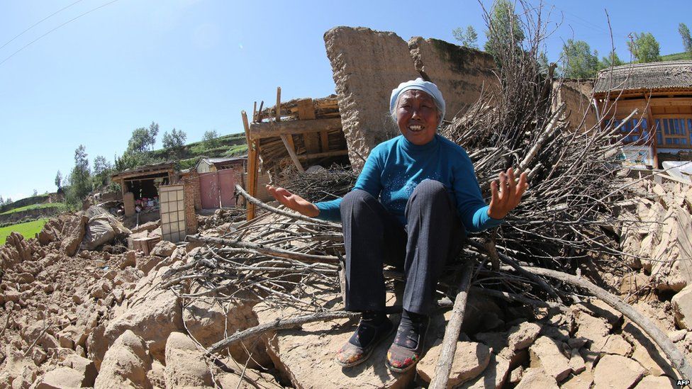 A resident cries on her collapsed house in Hetuo township in China's north-west Gansu province following two earthquakes on 22 July, 2013.