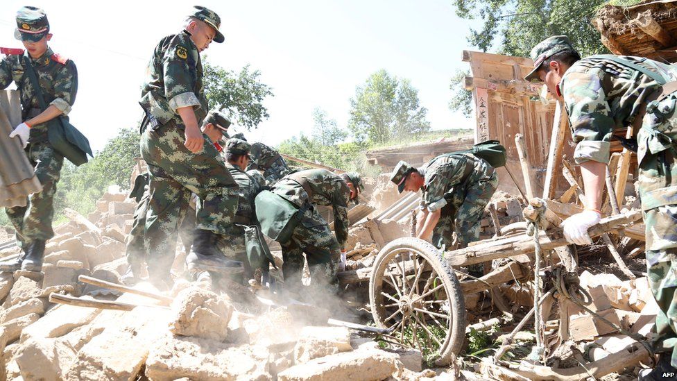 Rescuers use a wooden cart to search for survivors in the ruins of a damaged house in Hetuo township in China's north-west Gansu province following two earthquakes on 22 July, 2013.