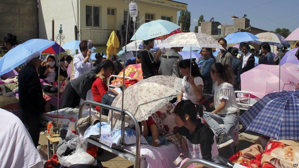 Residents holding umbrellas gather at a makeshift hospital after an earthquake hit Minxian county in north-west China's Gansu province on Monday 22 July 2013.