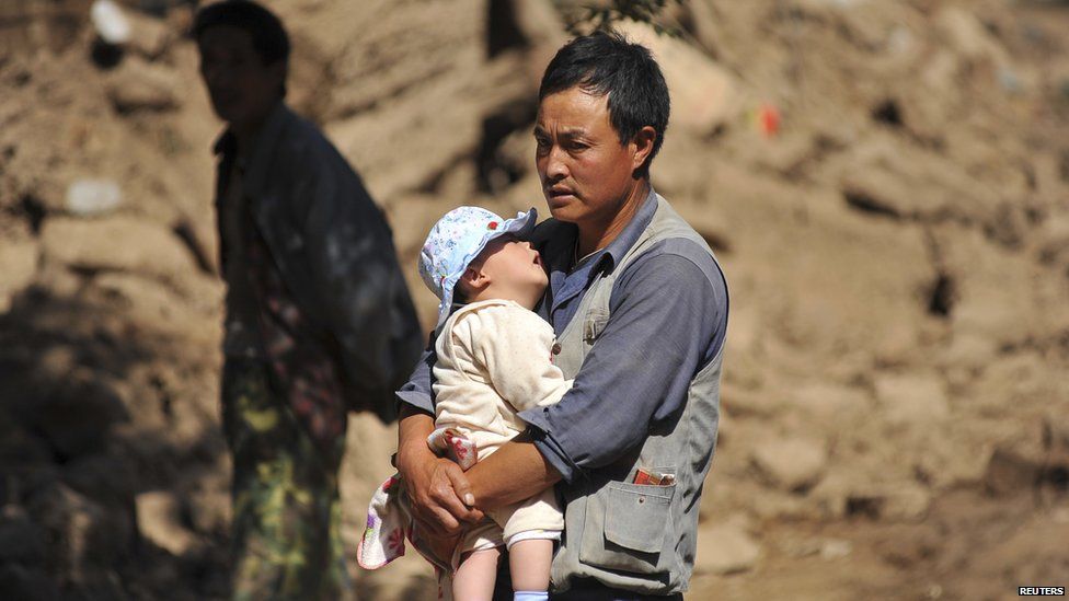 A man holds a baby after an earthquake in Minxian county, Dingxi, Gansu province, July 22, 2013