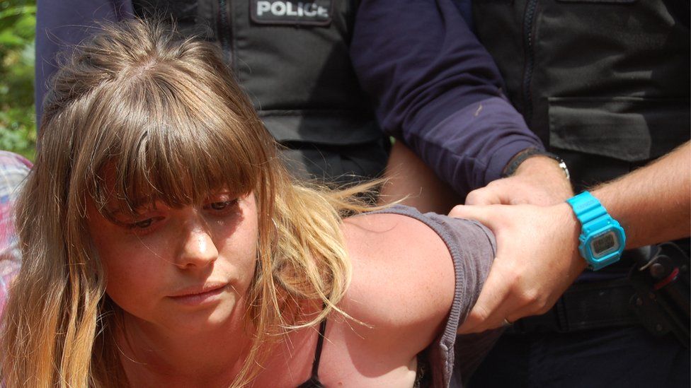 Woman having her arm held by police officer