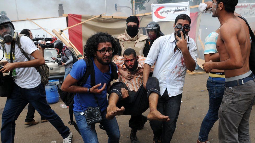 People carry an injured protester at Nahda Square in Cairo during clashes between supporters of Egypt's ousted president Mohammed Morsi and riot police on 14 August 2013