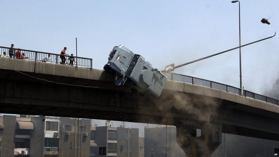 A police vehicle is pushed off of the 6th of October bridge by protesters close to the largest sit-in by supporters of ousted Islamist President Mohammed Morsi in the eastern Nasr City district of Cairo, Egypt, Wednesday, 14 August 2013