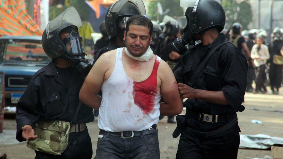 Egyptian riot police arrest a wounded demonstrator during clashes as security forces disperse protest camps on 14 August, 2012 that were set up in Cairo by supporters of Egypt's ousted President Mohamed Morsi