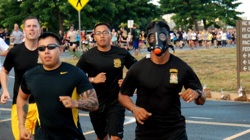 Runners in black attire, including one man in a gas mask.