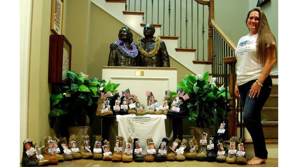 Theresa Johnson poses with a selection of boots with flags and photos attached