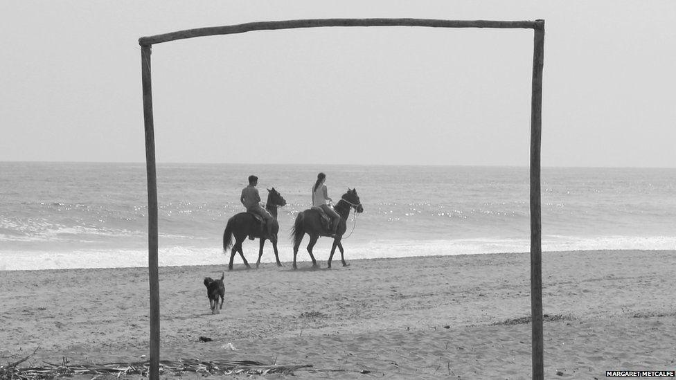 A couple ride horses on the beach