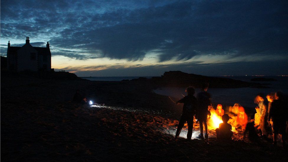 Scouts on a beach at dusk
