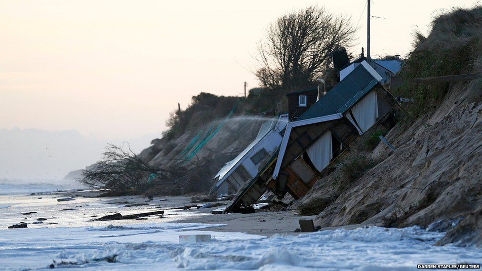 Collapsed houses lie on the beach after a storm surge in Hemsby, eastern England