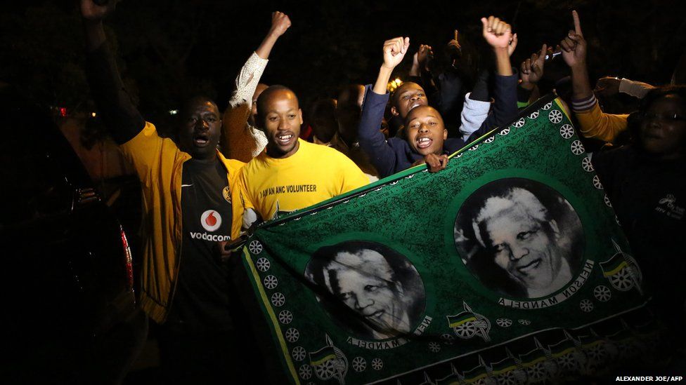 South Africans hold pictures of former South African president Nelson Mandela