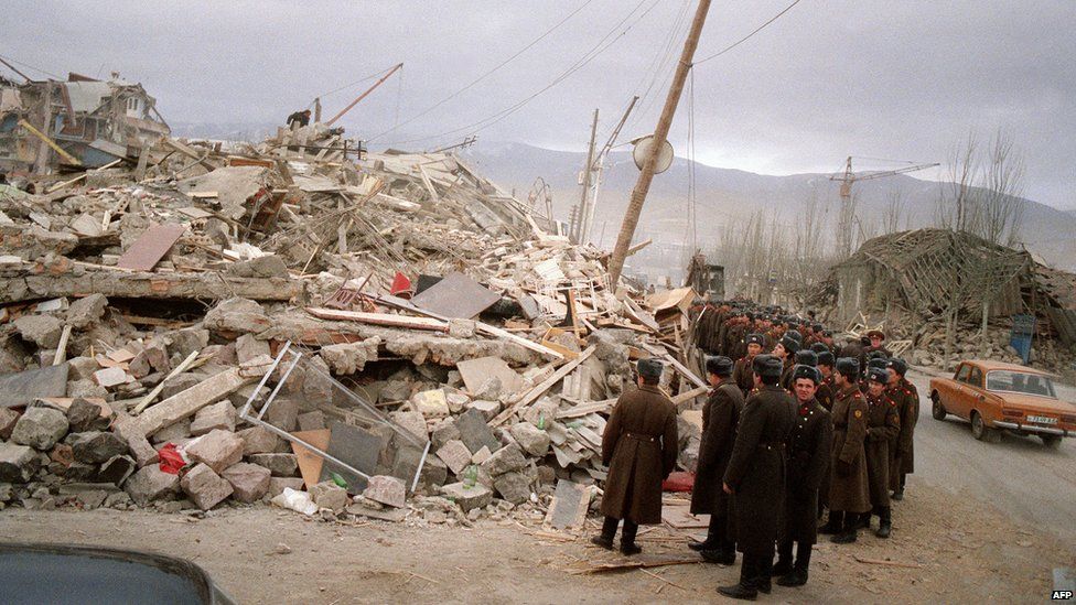 Soviet soldiers look at rubble in the devastated town of Spitak, on December 12, 1988, after an earthquake hit Armenia, on December 7, 1988.