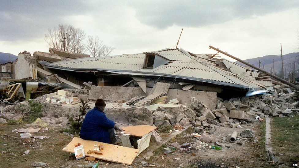 A Survivor sits near his house in the devastated town of Spitak, on December 11, 1988, after an earthquake hit Armenia, on December 7, 1988.