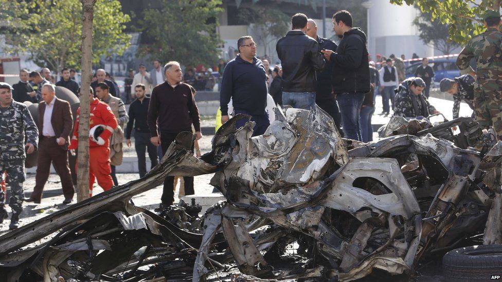 Onlookers and firemen gather around the remains of a vehicle that exploded in central Beirut (December 27, 2013)