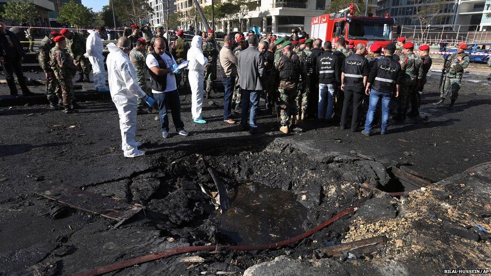 Lebanese army investigators in white coveralls stand next to a blast crater at the scene of an explosion in Beirut, Lebanon (Dec. 27, 2013)