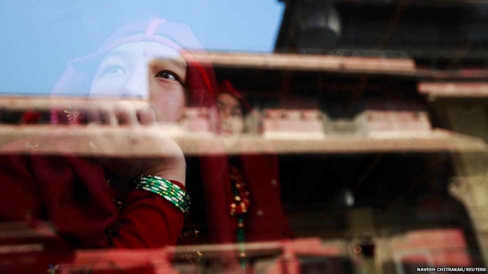 A Gurung girl wearing a traditional costume watches a passing New Year parade from inside a cafe in Kathmandu